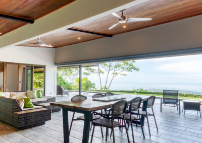A dining table and sectional couch under the covered breezeway with a view of the Whale's Tail.