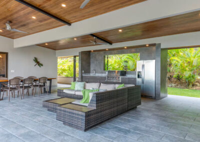 The covered breezeway with a sectional couch, dining area, and bbq grill/kitchen.