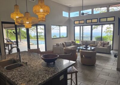Kitchen island with sink and living room with two comfy sleeper sofas with ocean view.