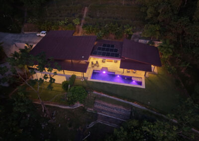 Aerial view of Villa Ballena with solar panels, infinity pool, and jungle landscape in Uvita, Costa Rica